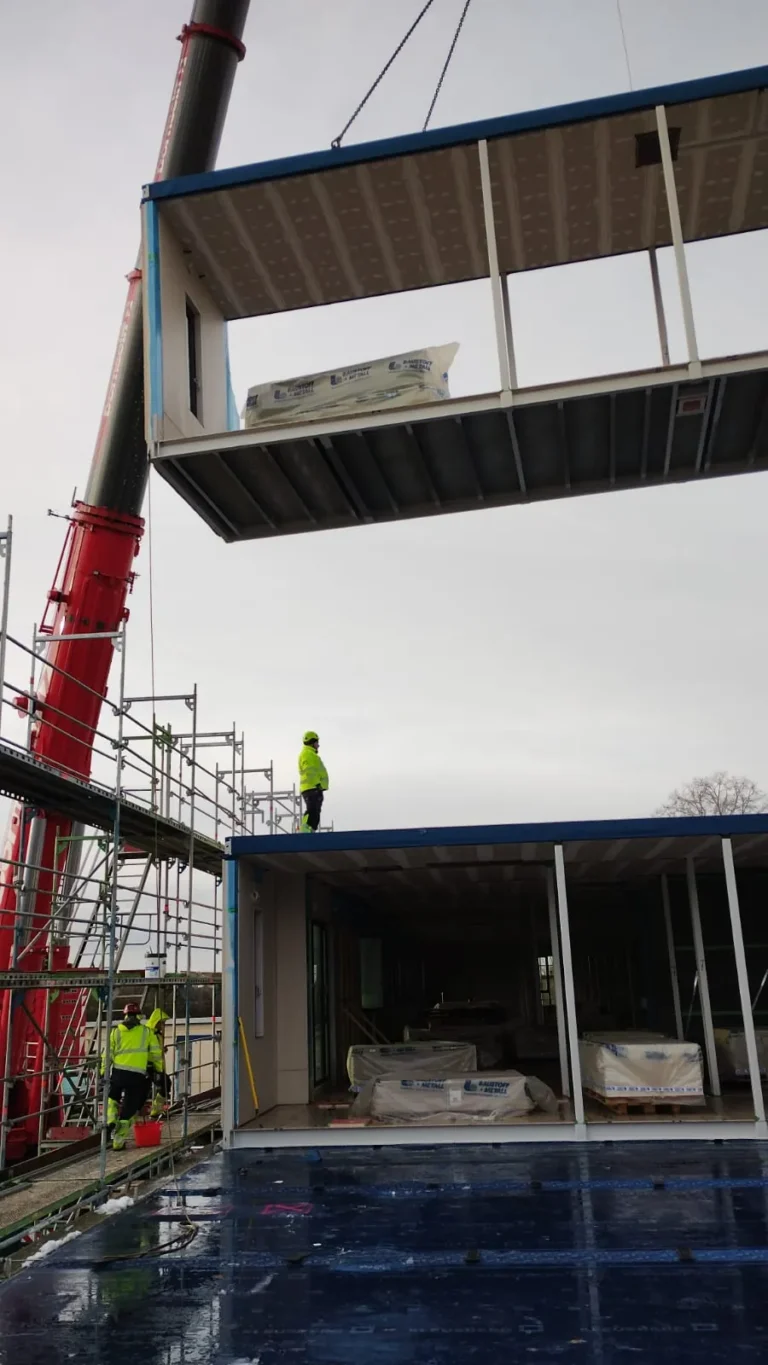 Montaż modułów szkoły w Hamburgu – dźwig ustawia moduł przestrzenny na poziomie rusztowania – WOHLFEIL